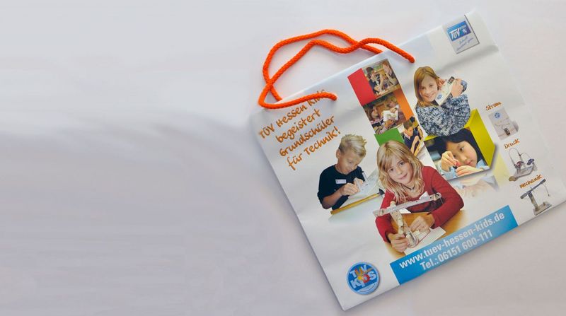Eine Werbetasche für ein pädagogisches Kinderprogramm mit Bildern von Kindern bei verschiedenen Aktivitäten, begleitet von einem Text in deutscher Sprache.